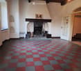 Empty room with a fireplace, checkered floor, and a window on the left side.