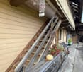 Wooden staircase leading up to a porch with a hanging decorative item, potted plants, and a small pumpkin on the railing.