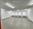 Empty room with white walls, concrete floor, and four windows with blinds. Radiators are visible under the windows.