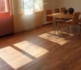 Bright dining area with wooden floor, large windows, dining table with chairs, and decorative spheres on the table.