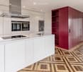 Modern kitchen with white cabinets, stainless steel appliances, a central island, and a red accent wall.