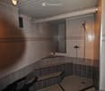 Modern bathroom with tiled walls and floor, built-in benches, a shower area, and a mirror above a small shelf.