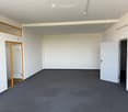 Empty room with white walls, grey carpeted floor, and two doors (one with glass panels).