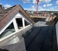 Roof terrace with modern glass enclosure, metal railing, and cityscape view in the background.