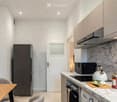 Modern kitchen with marble countertops, stainless steel appliances, and a small dining area.