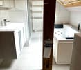 Modern bathroom with a sink, bathtub, radiator, mirror, and cabinets. Features a skylight window and wooden beam.