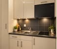Modern kitchen with light-colored cabinets, stainless steel sink, induction cooktop, and various small appliances and decor items.