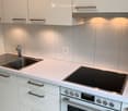 Modern kitchen with white cabinets, stainless steel sink, induction cooktop, and built-in oven.