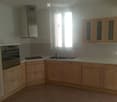 modern kitchen with light-colored wooden cabinets, tiled floor, sink with faucet, oven, window