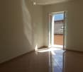 empty room with white walls, open sliding door, tile flooring, balcony