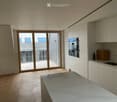 Modern kitchen with light-colored cabinets, a central island, and a sliding glass door leading to a balcony.