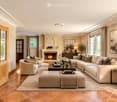 Elegant living room with a large sectional sofa, coffee table, armchairs, fireplace, and decorative items.