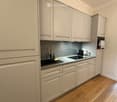 Modern kitchen with light-colored cabinets, a stainless steel sink, and a wooden floor.