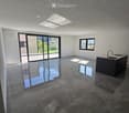 Empty room with dark stone tiles, large windows, and a modern kitchen island with a sink.