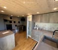 Modern kitchen with wooden ceiling, grey cabinets, stainless steel appliances, and a central island.