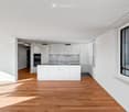 Modern kitchen with white cabinets, a central island, and a large window offering a view of the city.