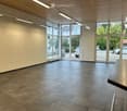 Empty room with tiled floor, large windows, and a door leading outside. No furniture or equipment present.