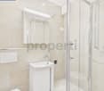 Modern bathroom with a white sink, a large mirror, and a glass-enclosed shower area.