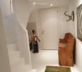 Modern hallway with white walls, staircase, wooden bench, and artwork on the wall.