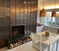 Modern dining area with a fireplace, white dining table, chairs, and pendant lights.