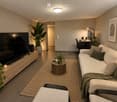 Modern living room with a white sofa, coffee table, TV stand, desk, and plants. Features a large flat-screen TV, a round coffee table, and a cozy seating area.