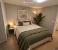 Modern bedroom with a neatly made bed, nightstand, table lamp, and decorative plants.