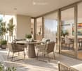 Modern balcony with a round table, wicker chairs, and potted plants, overlooking a scenic view.