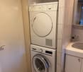 Bathroom with a washing machine and dryer stacked, a sink with a mirror, and tiled walls and floor.