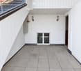 Modern balcony with white wooden paneling, tiled floor, large window overlooking a tiled roof, and a small window in the center.