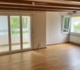 Empty room with wooden flooring, large sliding glass doors leading to a balcony, and white walls.