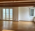 Empty room with wooden flooring, white walls, large sliding glass doors, and a window with blinds.