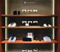 Wooden shelves with neatly folded ties, shirts, and bow ties, illuminated by soft lighting. Includes decorative boxes and a framed picture.