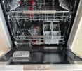 Stainless steel dishwasher with multiple racks and compartments, featuring a control panel with various settings and a digital display showing the time.