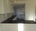 Modern kitchen with white cabinets, black countertop, built-in oven, and sink. The space is well-lit with recessed lighting and features a sleek, contemporary design.