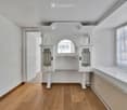 Empty room with wooden flooring, white walls, built-in white cabinetry with glass doors, and a large window with white curtains.