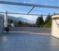 A modern balcony with tiled flooring, metal railings, and a scenic mountain view in the background.