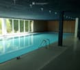 Indoor swimming pool area with large windows, modern concrete ceiling, and wooden paneling.