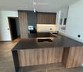 Modern kitchen with dark wooden cabinets, a central island, and built-in appliances.