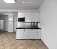 Modern kitchen with white cabinets, a microwave, a sink, and a faucet, featuring tiled flooring and white walls.