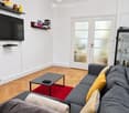 Modern living room with grey sofa, coffee table, television, shelves, and decorative items.