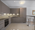 Modern kitchen with grey cabinets, stainless steel appliances, a coffee maker, and a bar area with stools.
