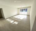 Empty room with white walls, wooden floor, and sliding glass doors leading to a balcony.