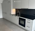 Modern kitchen with white cabinets, black countertops, stainless steel sink and faucet, and built-in oven.
