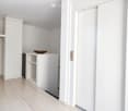 A modern, minimalist hallway with a built-in wardrobe, coat rack, small plant, and a decorative bowl on a shelf.
