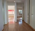Empty hallway with wooden flooring, white walls, and doors leading to other rooms.