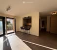 Open-plan living and dining area with wooden flooring, modern kitchen area, and access to a balcony.