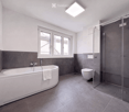Modern bathroom with a bathtub, toilet, glass-enclosed shower, and a window providing natural light.