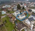 Aerial view of a residential area with multiple houses, surrounded by greenery and other structures.