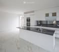 Modern kitchen with white cabinets, black countertops, and a central island. Features a built-in oven and a sink with a modern faucet.