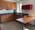 Modern kitchen with wooden cabinets, black countertops, a sink, and a central island.